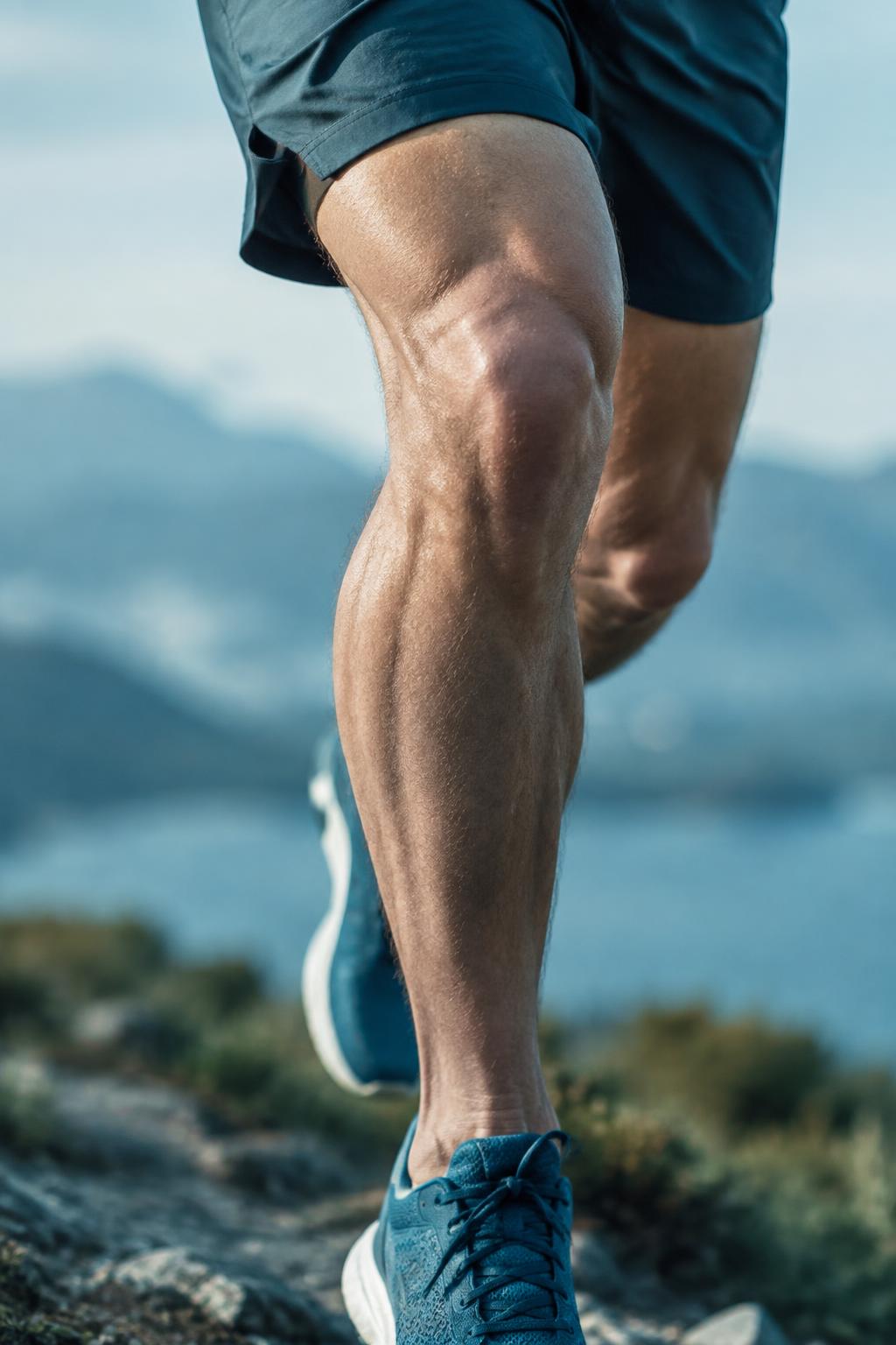 Close-up of an athlete's knee and leg mid-stride on a mountain trail